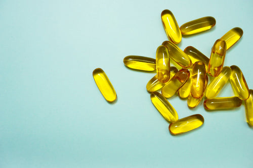 Cápsulas softgel amarelas de vitamina D3 sobre fundo azul