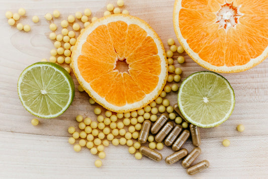 Cápsulas de vitamina C ao lado de laranja e limão